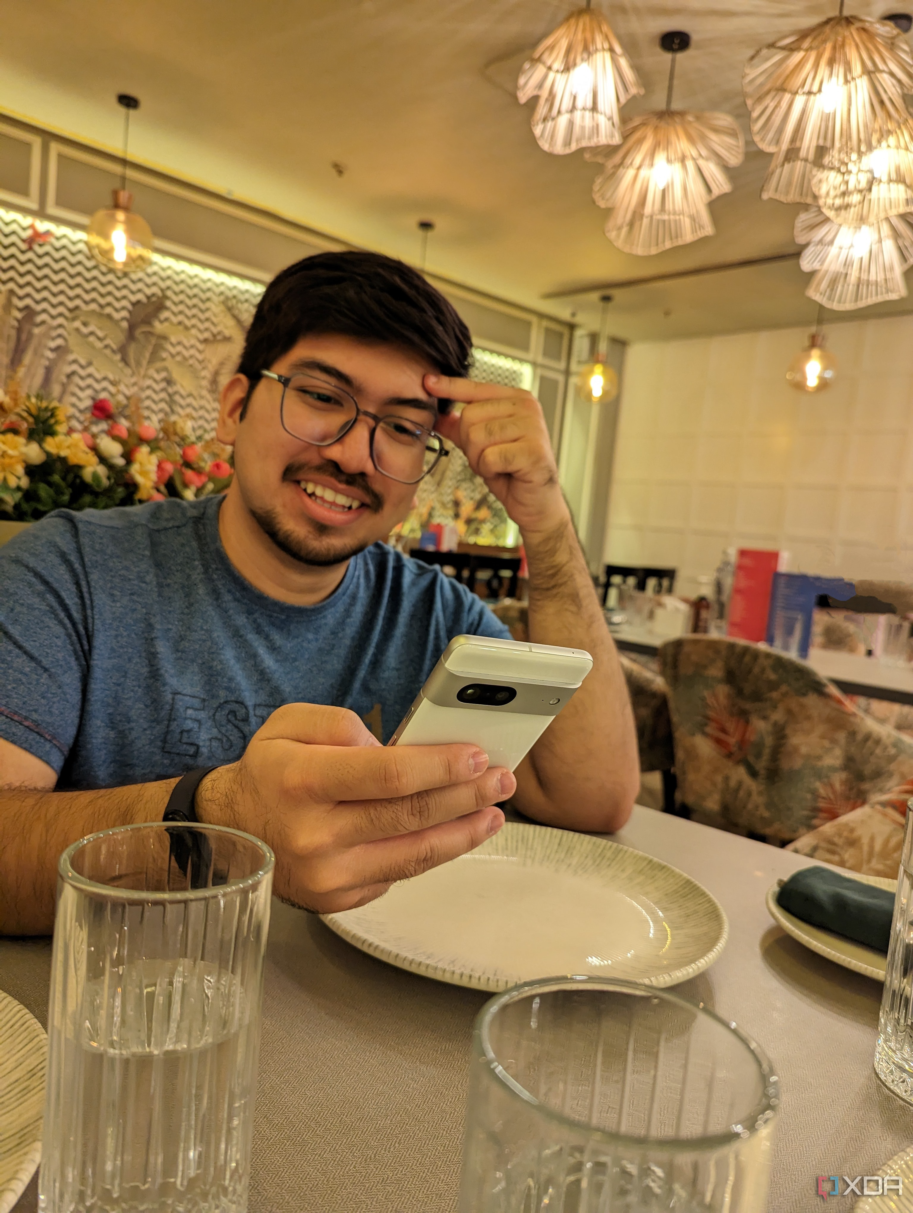 An image of person sitting on a dining table with a phone in their hand.