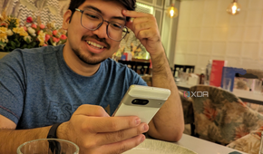 An image of person sitting on a dining table with a phone in their hand.