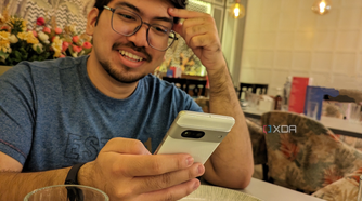 An image of person sitting on a dining table with a phone in their hand.