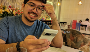 A image showing a person sitting on a dining table with a phone in their hand.