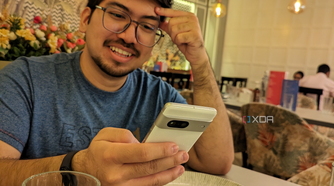 A image showing a person sitting on a dining table with a phone in their hand.
