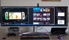 Front view of a desk with the LG UltraWide 49W95C monitor, a laptop, and various peripherals.