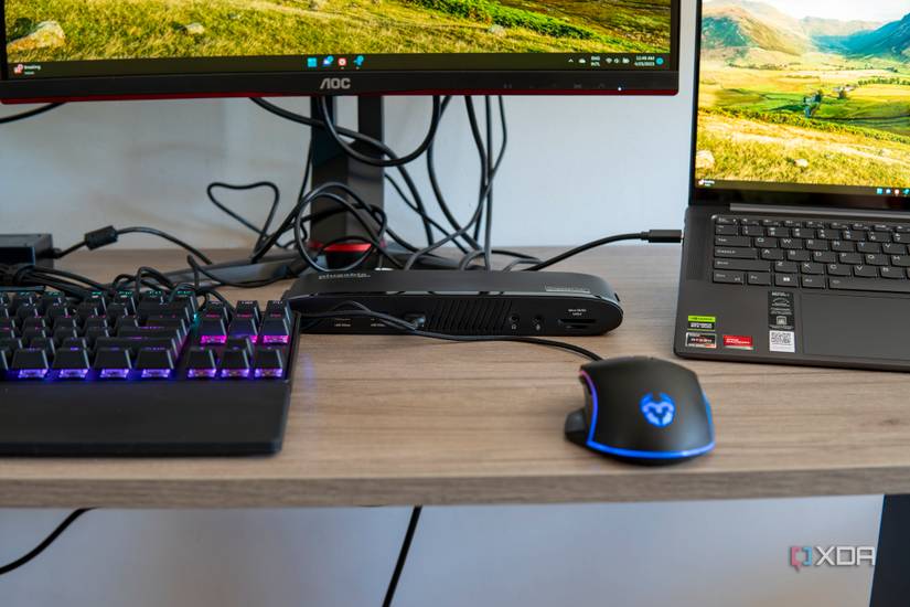 A Plugable UD-3900PDH docking station next to a laptop and multiple peripherals which are connected to it
