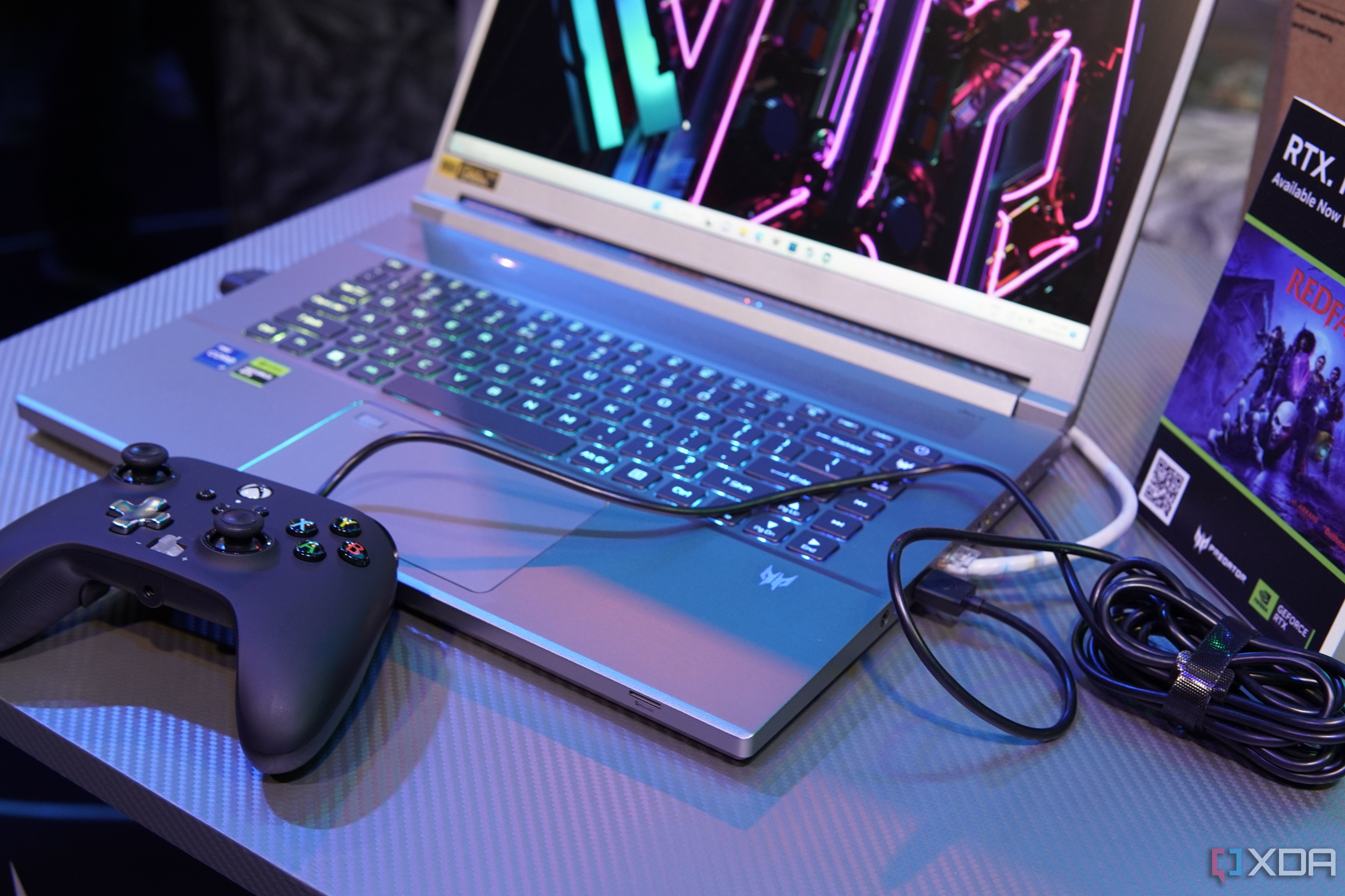 Angled view of the Acer Predator Triton 16's keyboard with the laptop facing left. A USB controller and an Ethernet cable are plugged into the laptop.