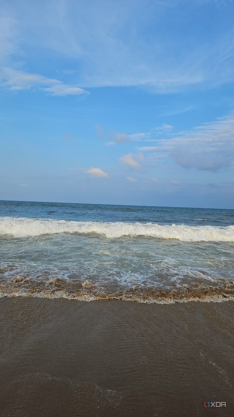 A image showing a beach-side view with bright blue sky, lots of water, and sand.