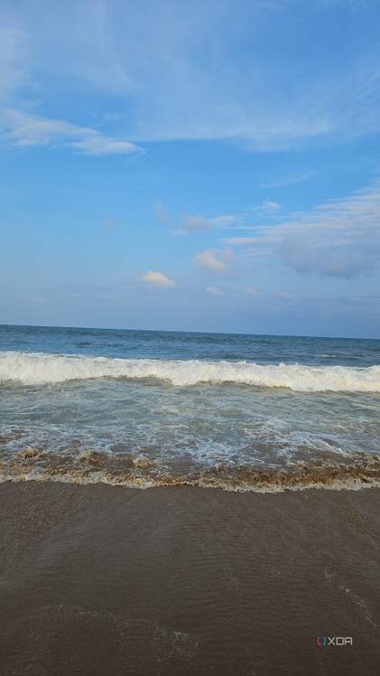 A image showing a beach-side view with bright blue sky, lots of water, and sand.