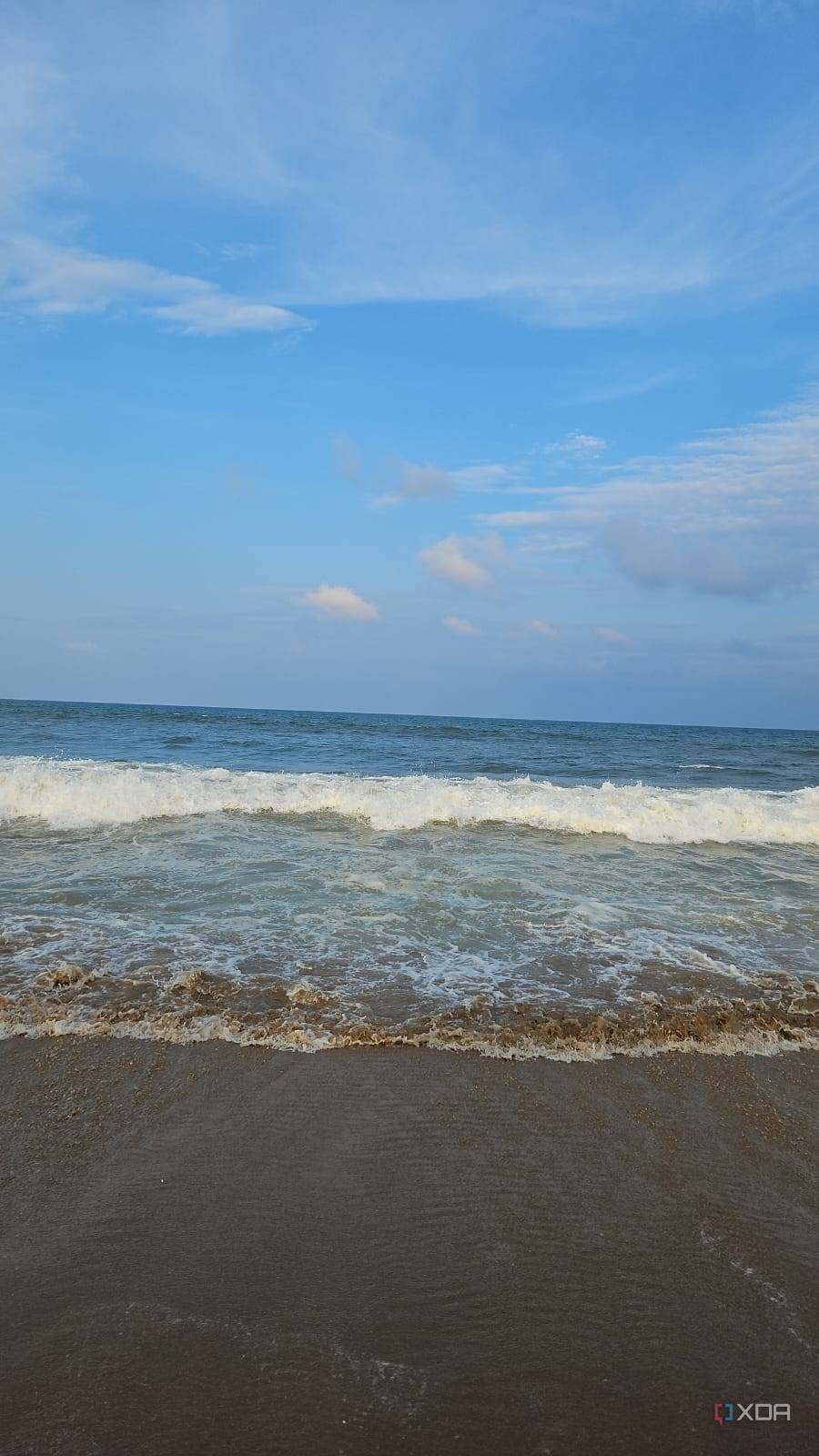 A image showing a beach-side view with bright blue sky, lots of water, and sand.