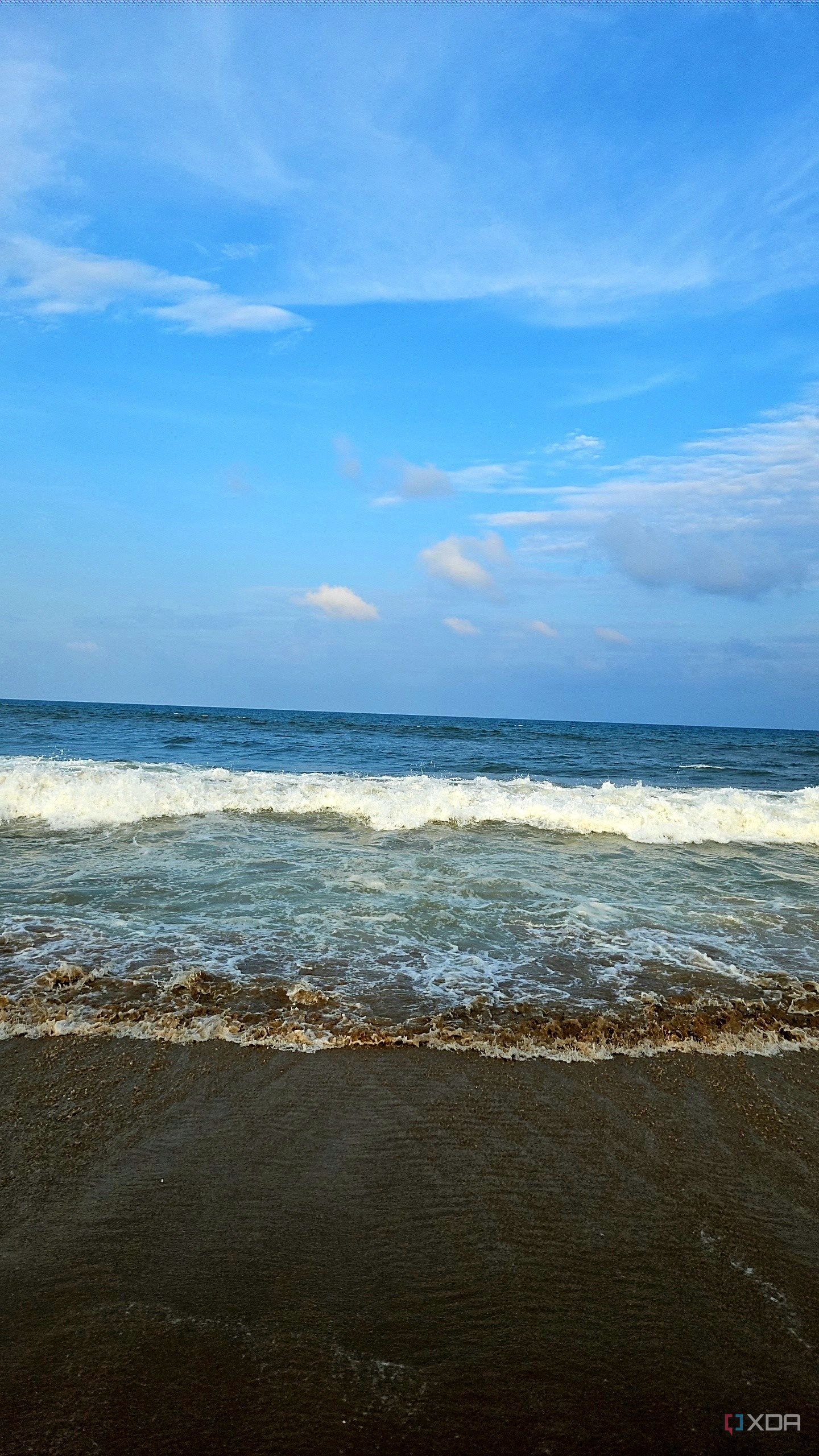 A image showing a beach-side view with bright blue sky, lots of water, and sand.