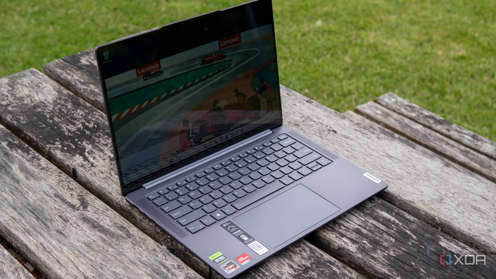 Angled front view of the Lenovo Slim Pro 7 on a wooden table with grass in the background