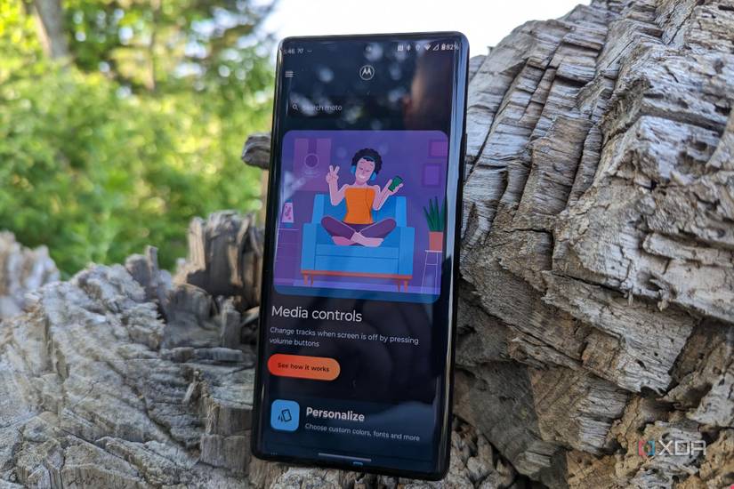 Motorola Edge+ 2023 leaning on a tree stump showing the Motorola media controls