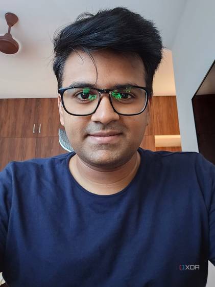 A selfie of a man wearing a blue-colored shirt with wooden wardrobe in the background.