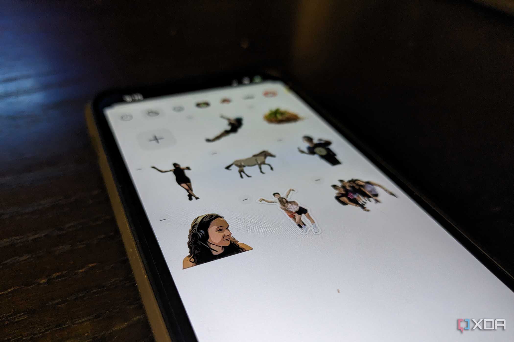 An iPhone 14 on an angle showing a variety of custom stickers in a Sticker drawer