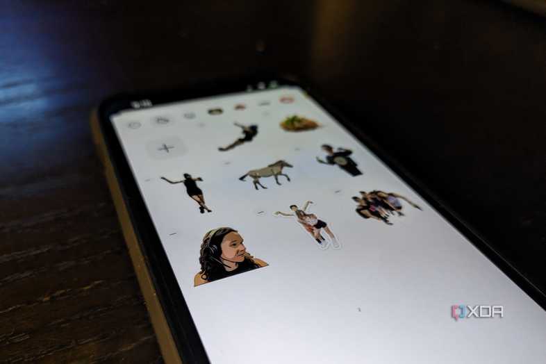 An iPhone 14 on an angle showing a variety of custom stickers in a Sticker drawer