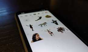 An iPhone 14 on an angle showing a variety of custom stickers in a Sticker drawer