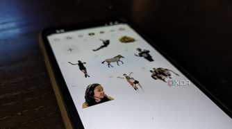 An iPhone 14 on an angle showing a variety of custom stickers in a Sticker drawer
