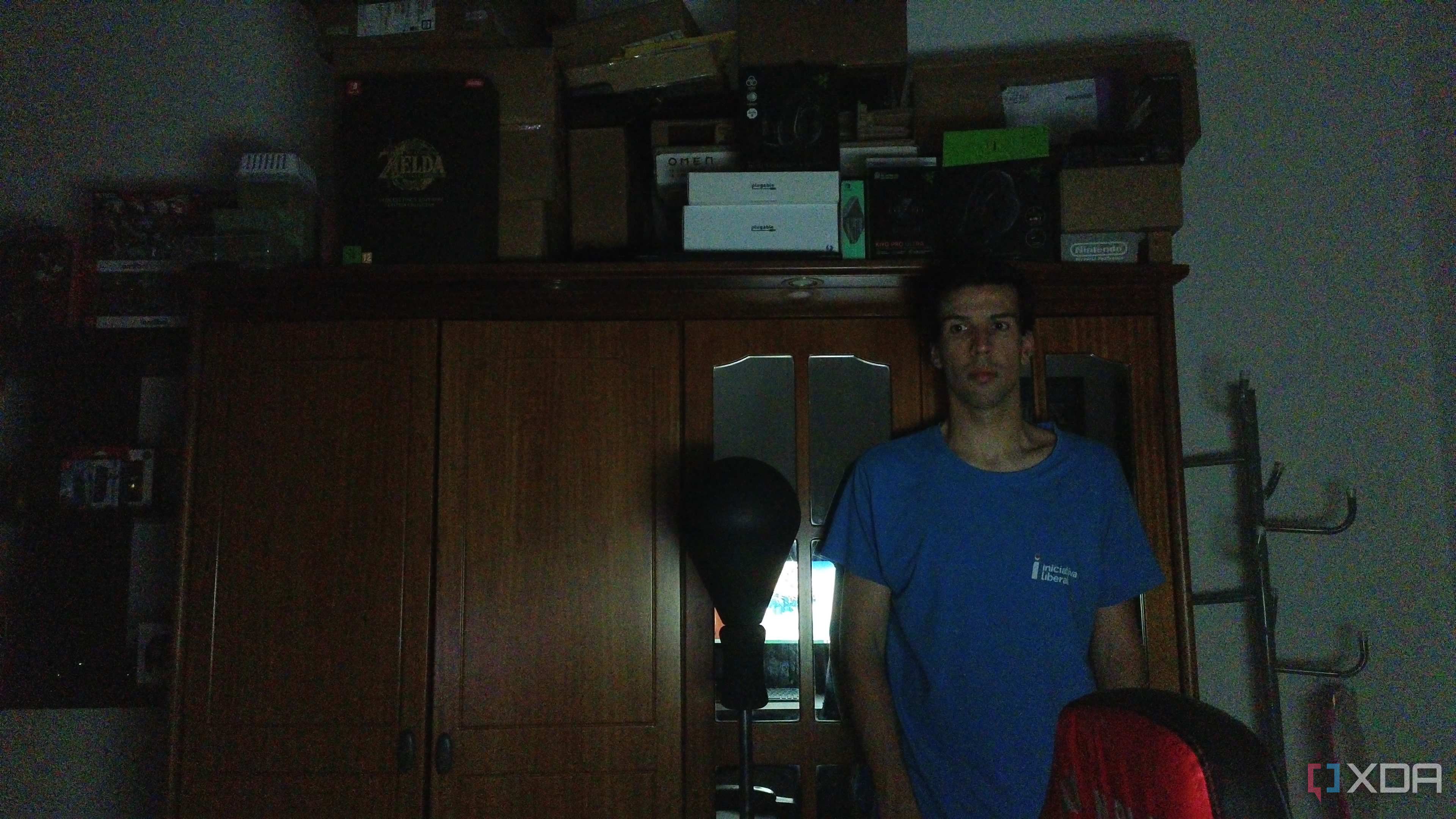 A man standing in a dark room in front of a wardrobe. He's slightly to the left in the frame because the webcam wasn't able to track his position in the dark