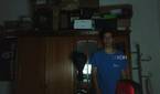 A man standing in a dark room in front of a wardrobe. He's slightly to the left in the frame because the webcam wasn't able to track his position in the dark