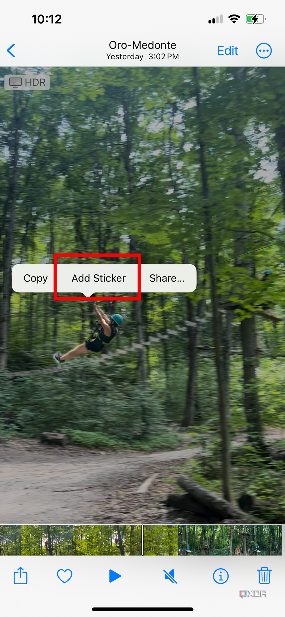 A paused video on an iPhone of a woman ziplining, the Add Sticker pop-up menu highlighted.