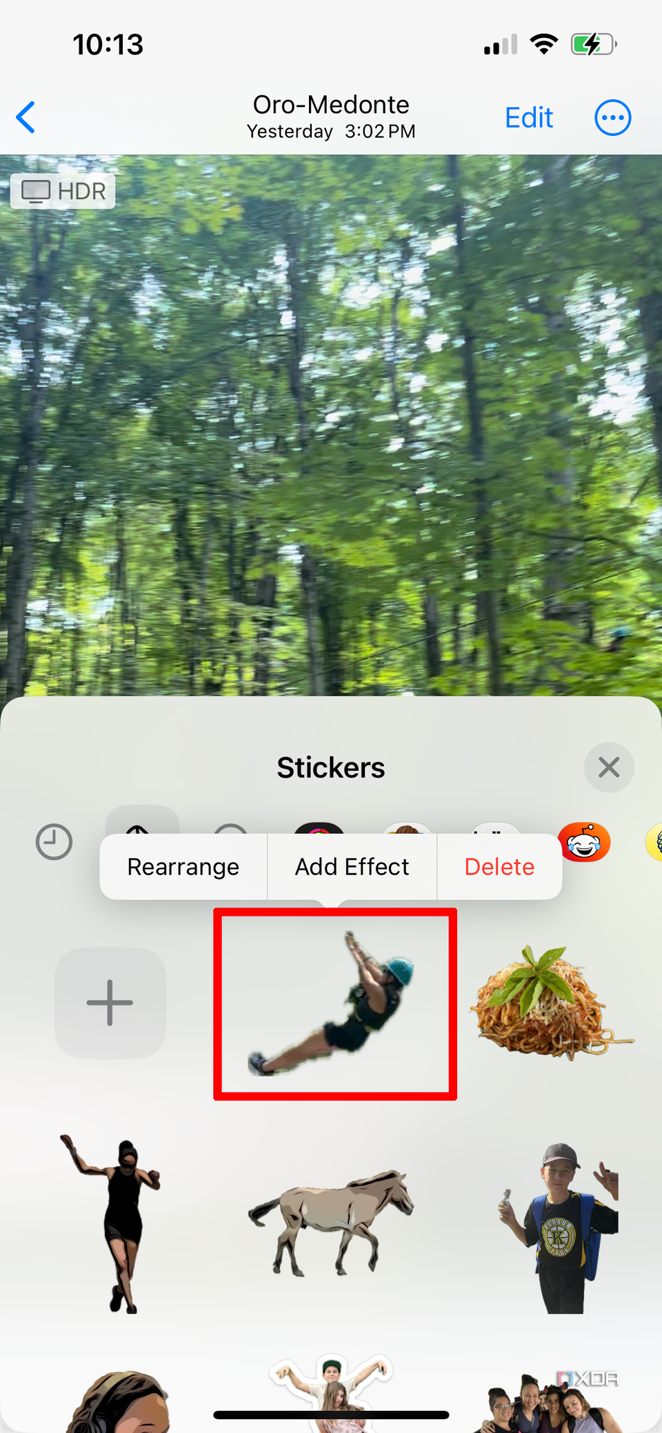 A video on an iPhone in the background, the sticker drawer above it showing a woman ziplining turned into a custom sticker.