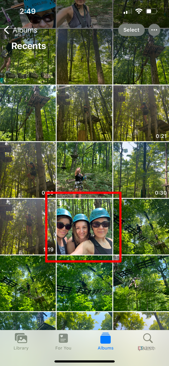 A photo library page on an iPhone with an image of three women wearing headgear selected.