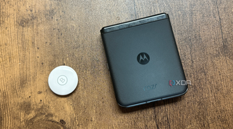 An Apple AirTag next to a Motorola Razr+ against a wood background.