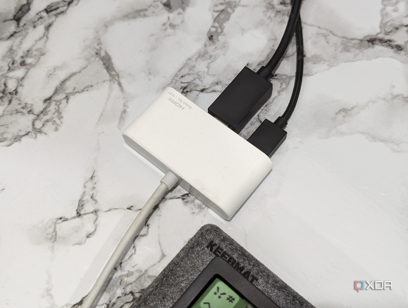 An image showing an HDMI multiport adapter kept on a desk next to a keyboard.