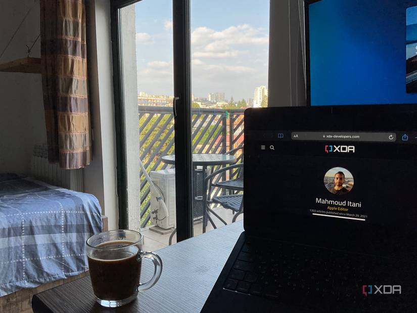 MacBook Air M2 showing mirrored iPhone screen next to coffee mug on a table
