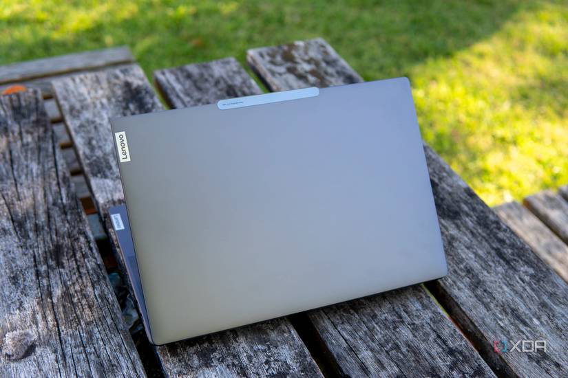 Rear angled view of the Lenovo Slim Pro 9i 14-inch laptop on a wooden table with grass in the background