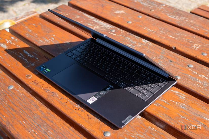 Angled front view of the Lenovo Slim Pro 9i 16-inch laptop on a wooden table with the lid open at roughly 60 degrees