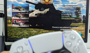 An image showing a PS5 DualSense controller with a monitor in the background running War Thunder Mobile game on DeX.