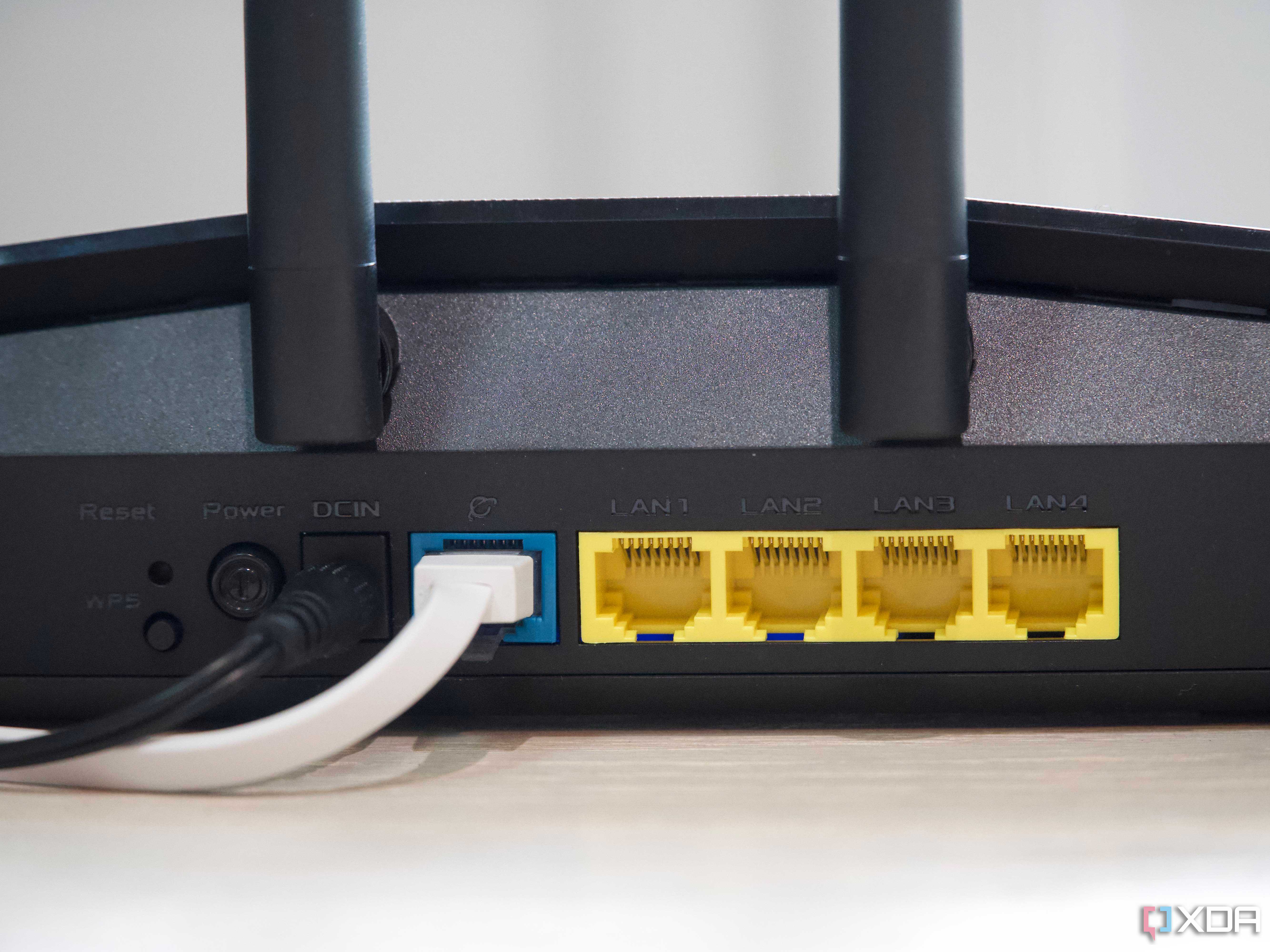 Asus RT-AX57 four open yellow Ethernet ports, one occupied blue port