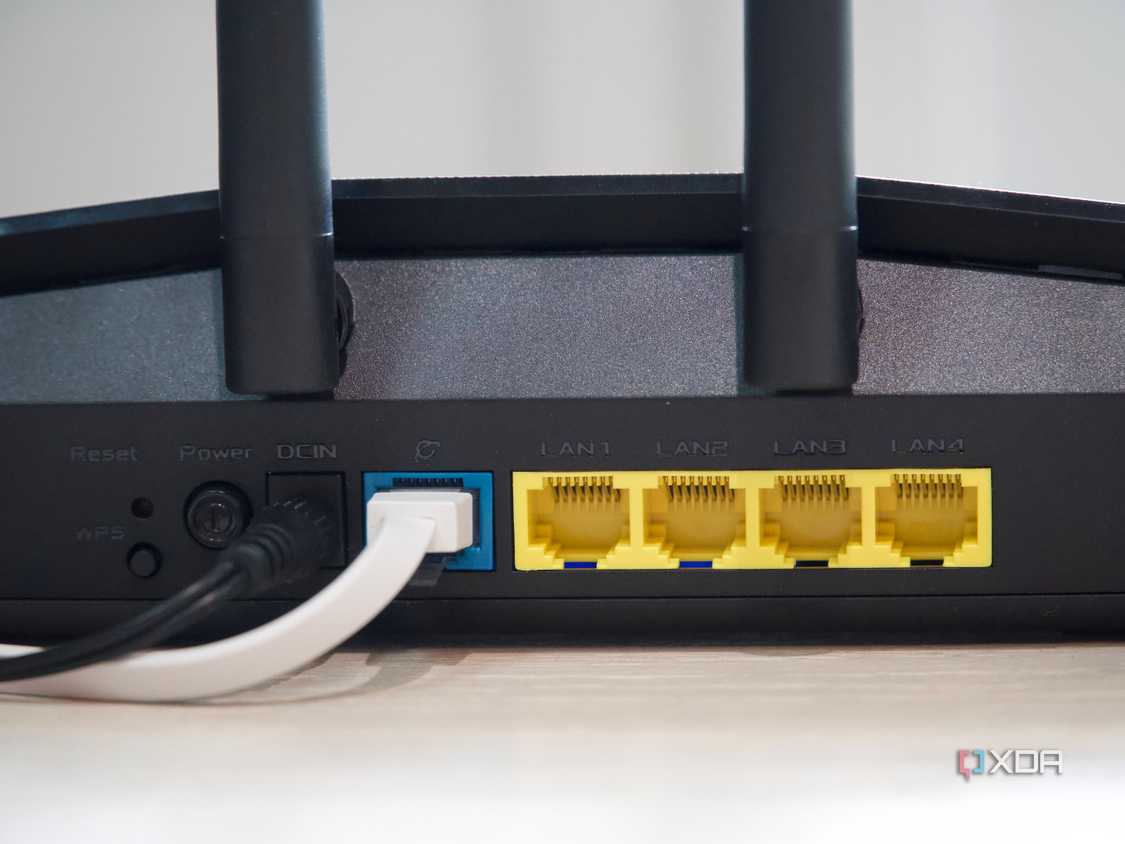 Asus RT-AX57 four open yellow Ethernet ports, one occupied blue port