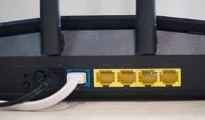 Asus RT-AX57 four open yellow Ethernet ports, one occupied blue port