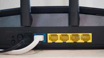 Asus RT-AX57 four open yellow Ethernet ports, one occupied blue port