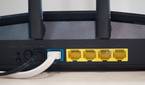 Asus RT-AX57 four open yellow Ethernet ports, one occupied blue port