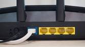 Asus RT-AX57 four open yellow Ethernet ports, one occupied blue port