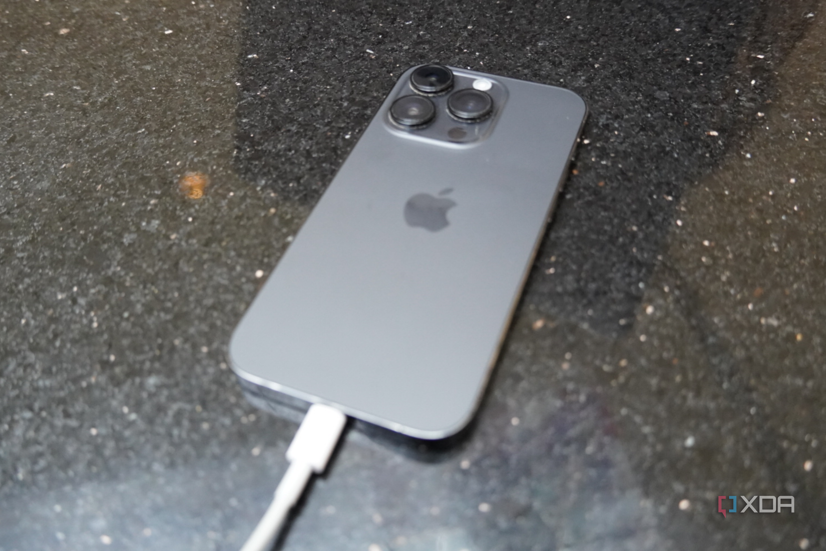 An iPhone 14 Pro connected to a Lightning charger.