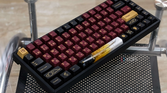An image showing a Keychron K2V2 keyboard with GMK Red Samurai keycaps kept on a glass table.