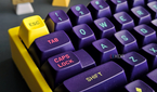 An image of a mechanical keyboard with a yellow case and purple MT3 keycaps.