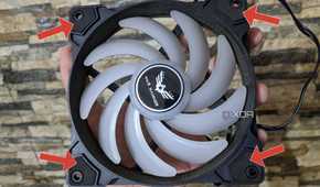 An image of a cabinet fan with arrows pointing at the rubber pads around the screw slots.