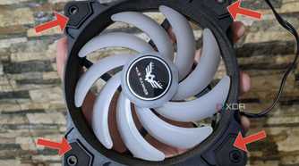An image of a cabinet fan with arrows pointing at the rubber pads around the screw slots.