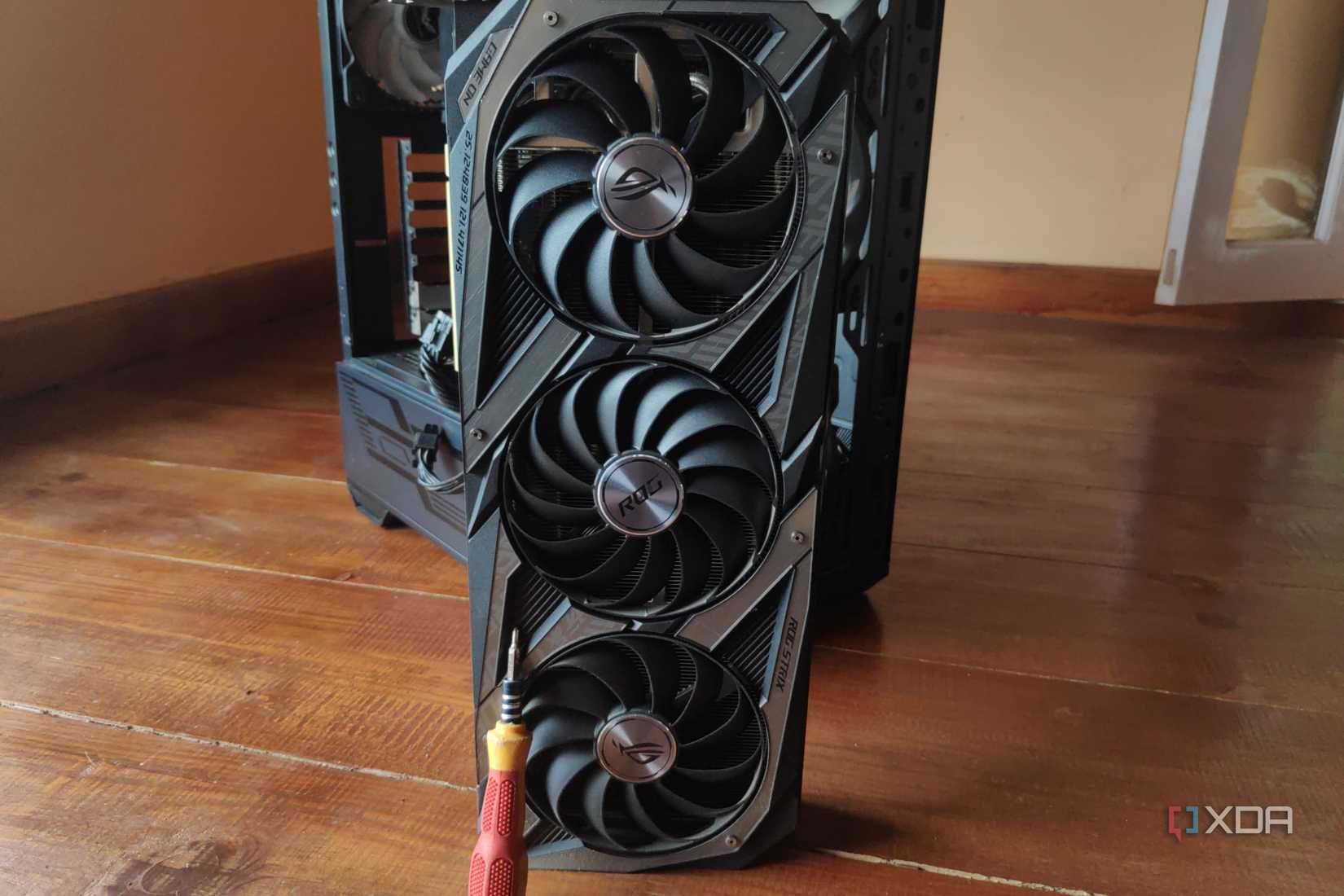 A screwdriver resting on an RTX 3080 Ti, with an MSI MAG Forge 110R in the background.