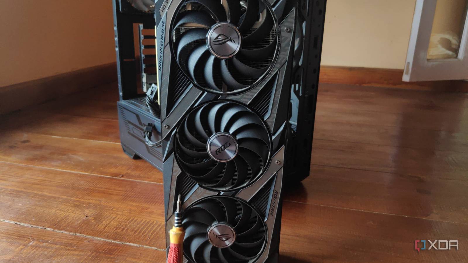 A screwdriver resting on an RTX 3080 Ti, with an MSI MAG Forge 110R in the background.