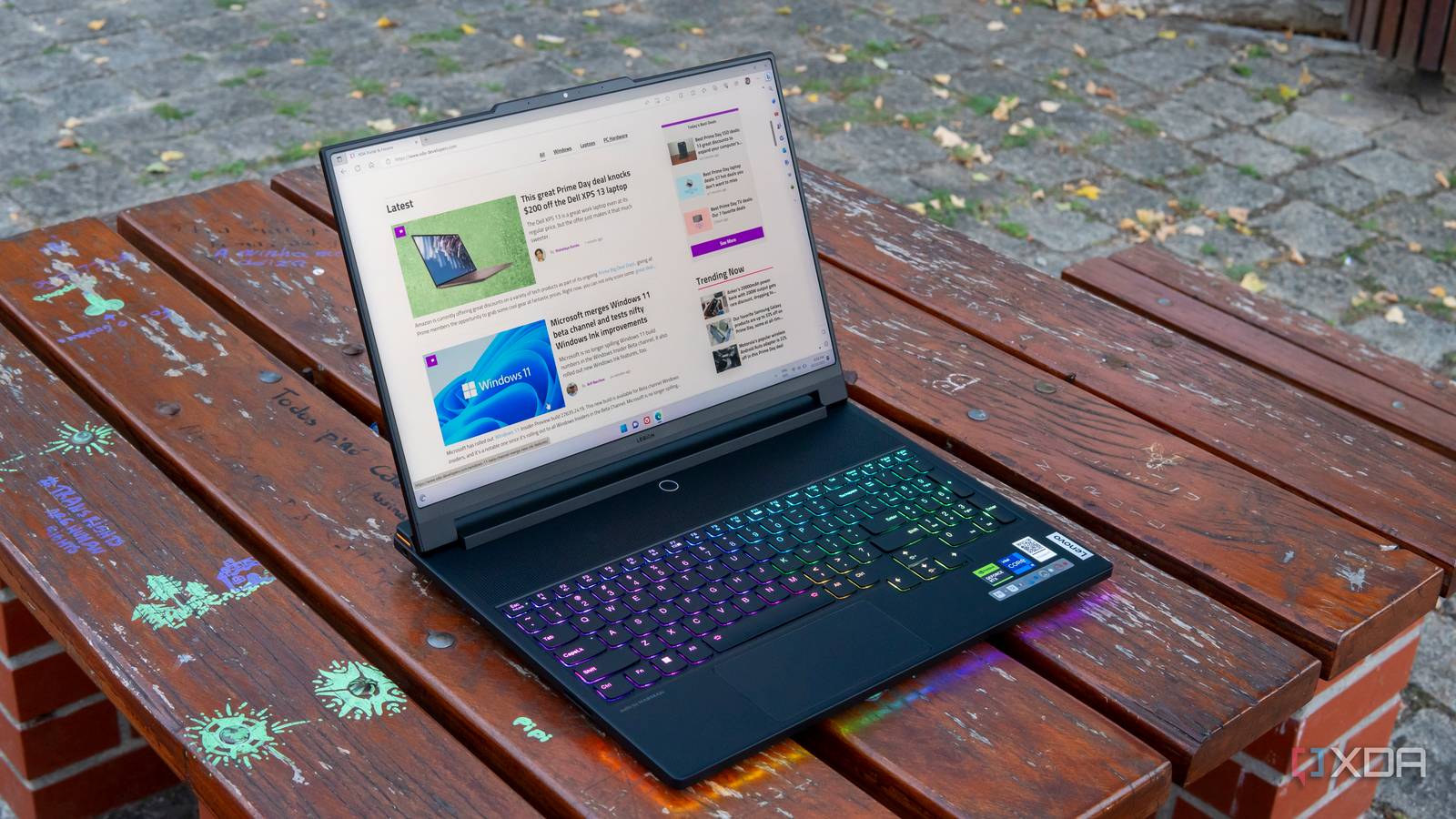 A Lenovo Legion 9i laptop on a wooden table, displaying the XDA homepage 