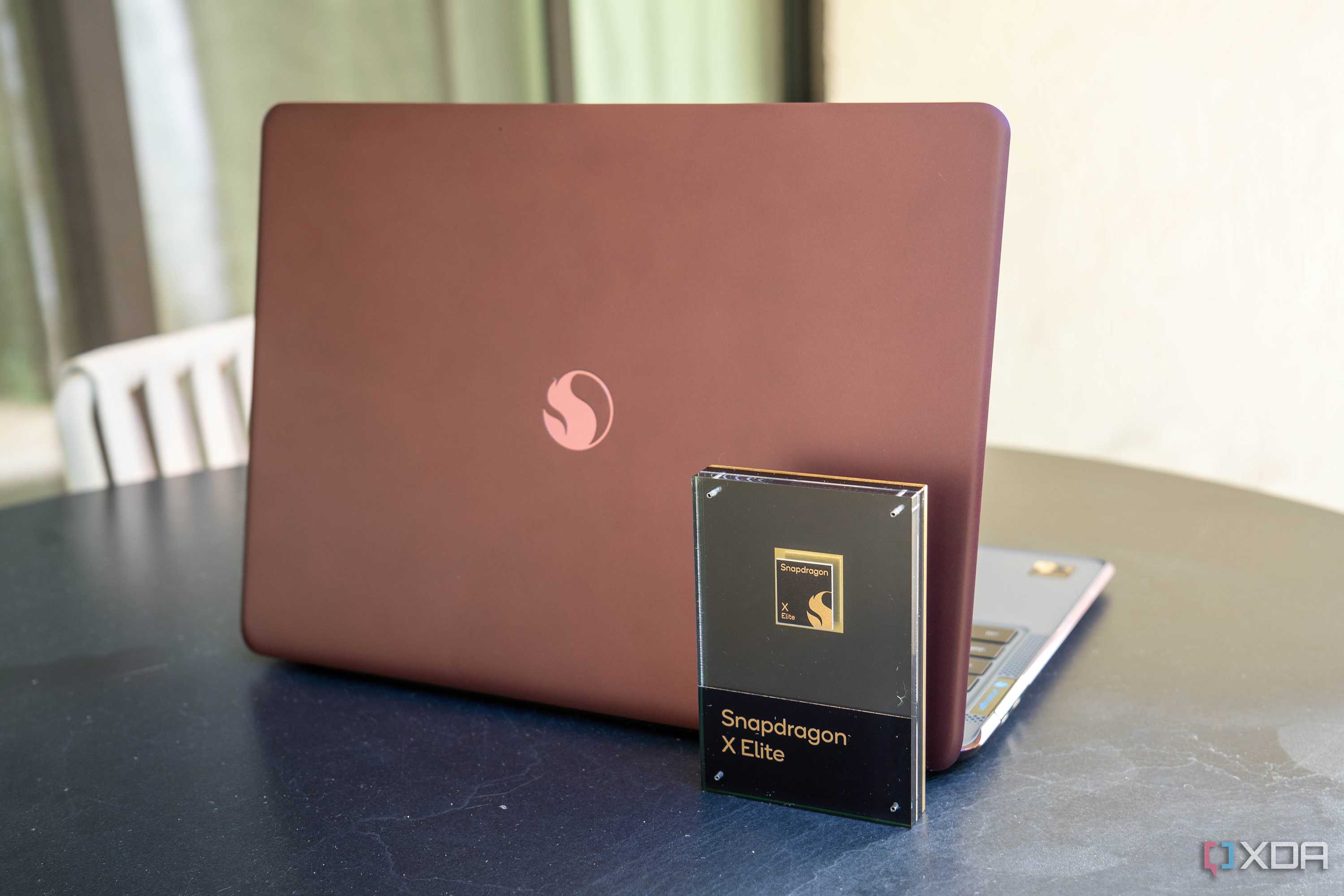 Snapdragon X Elite chip in front of a reference design laptop powered by the chip