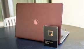 Snapdragon X Elite chip in front of a reference design laptop powered by the chip