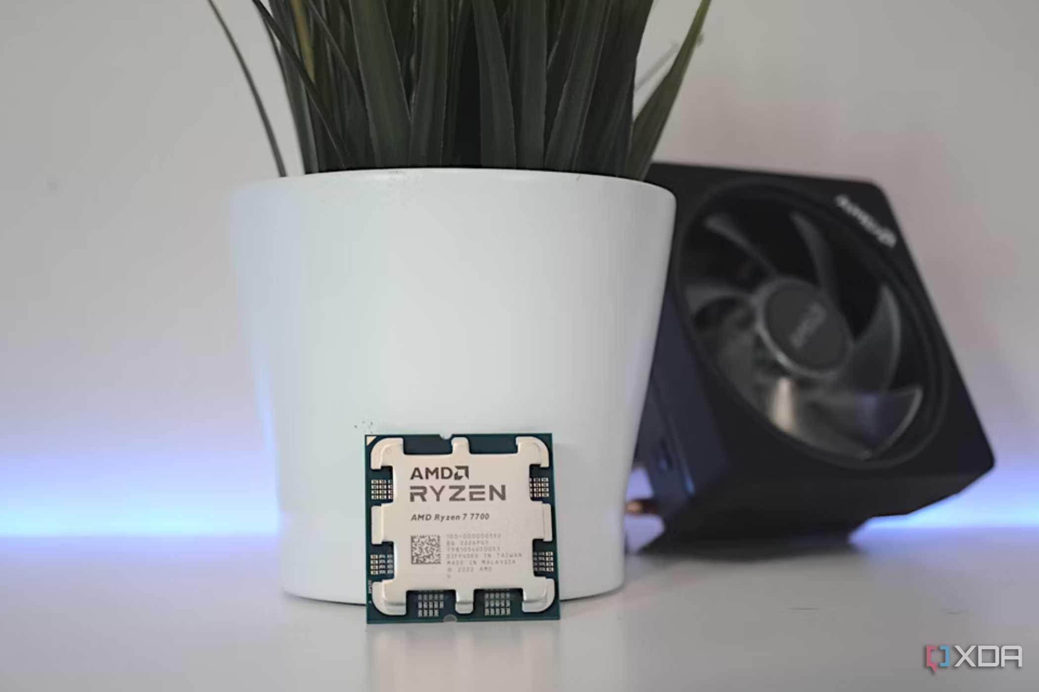 An image showing the AMD Ryzen 7 7700 CPU next to its cooler.