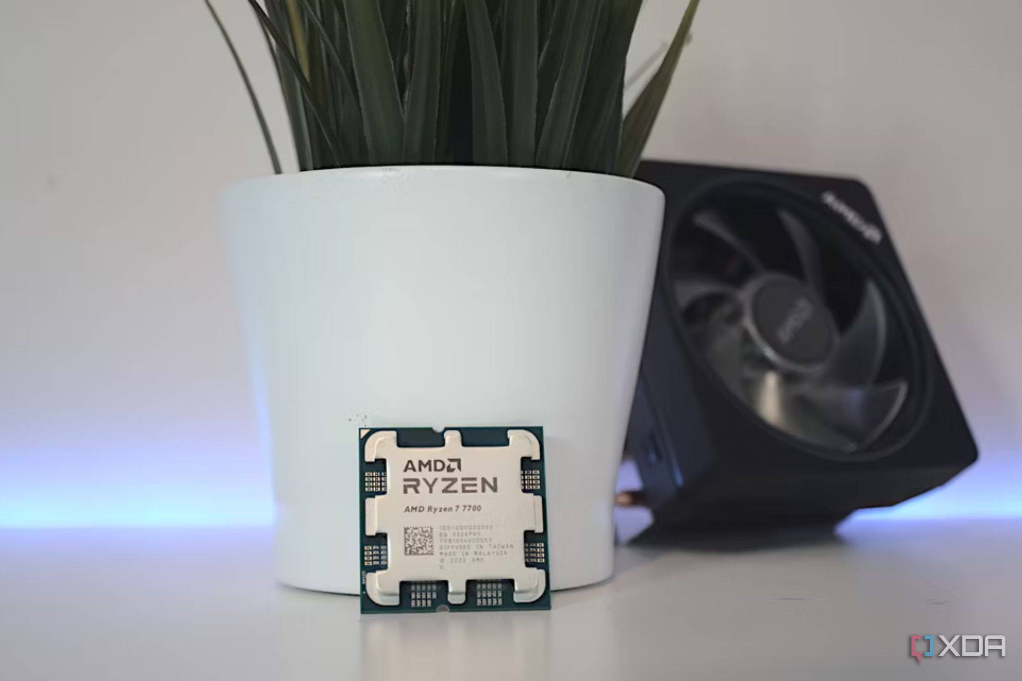 An image showing the AMD Ryzen 7 7700 CPU next to its cooler.