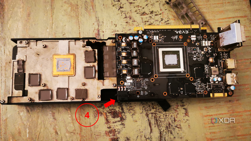 Graphics card lying outside the computer case, with the heatsink and thermal paste visible, and a label pointing at the fan power cable