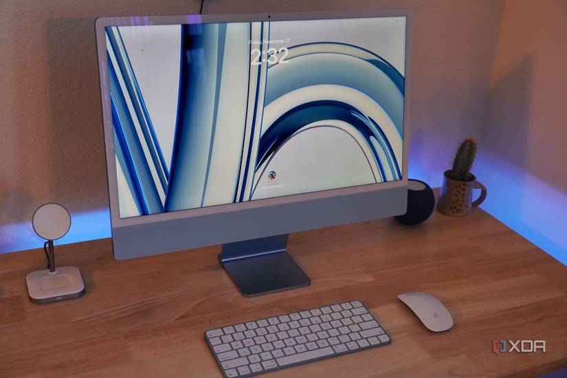 A blue M3 iMac on a desk with peripherals and accessories.